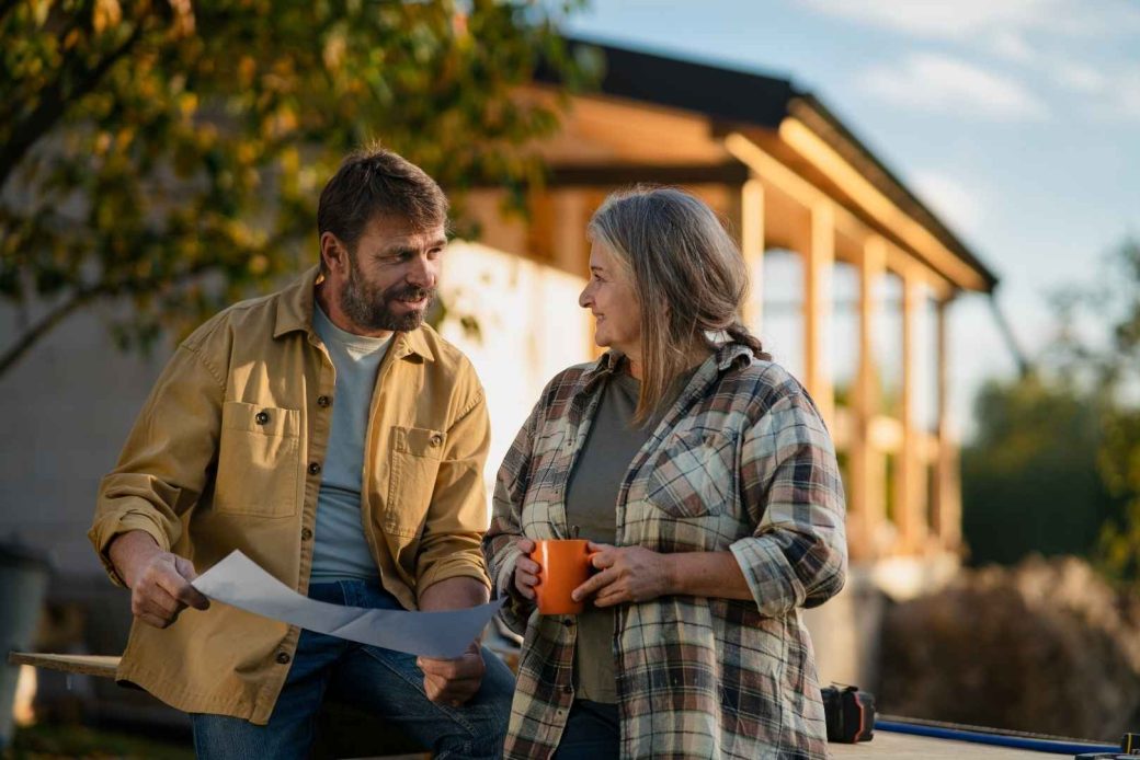 Woman with a cup of coffee talking to a contractor about home improvement plans